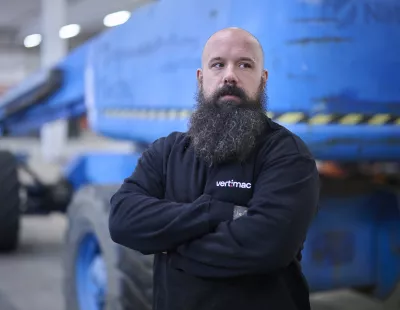 Vertimac Chef d'équipe devant une nacelle élévatrice, les bras croisés.